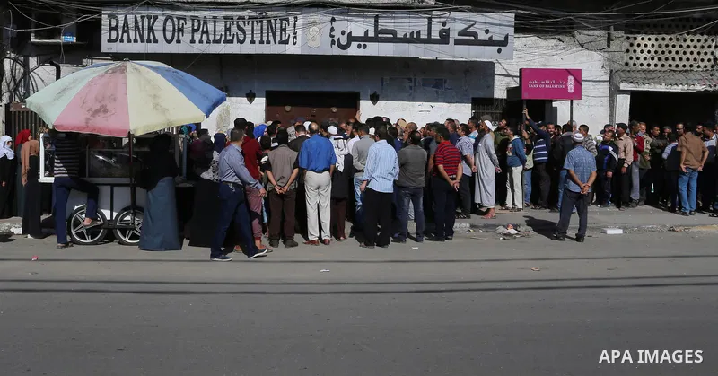 Palestinians of Social Affairs wait in front of Bank of Palestine to withdrew their financial aid in Gaza City on October 29, 2017. Photo by Yasser Qudih