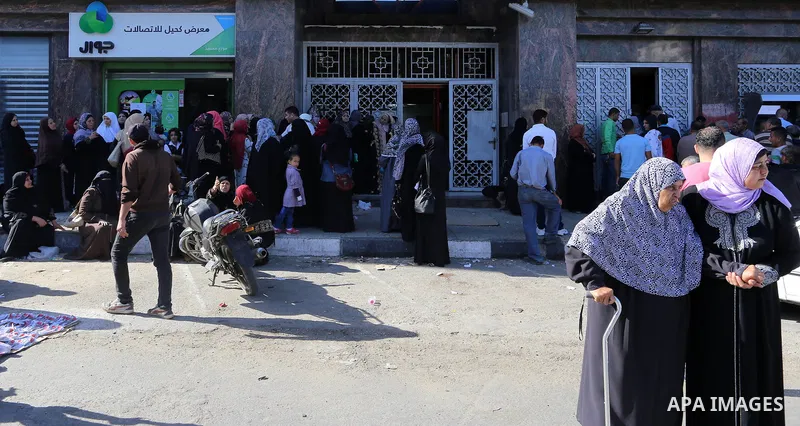 Palestinians of Social Affairs wait in front of Bank of Palestine to withdrew their financial aid in Gaza City on October 29, 2017. Photo by Yasser Qudih