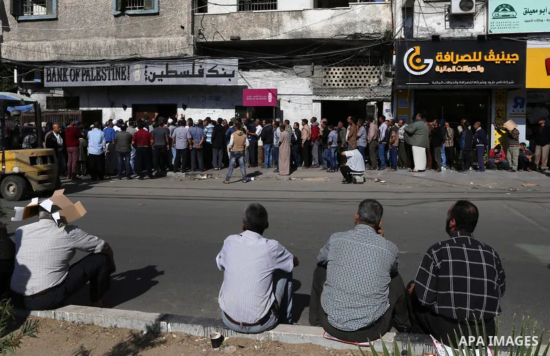 Palestinians of Social Affairs wait in front of Bank of Palestine to withdrew their financial aid in Gaza City on October 29, 2017. Photo by Yasser Qudih