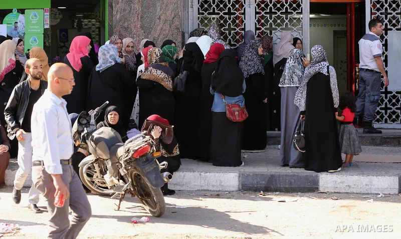 Palestinians of Social Affairs wait in front of Bank of Palestine to withdrew their financial aid in Gaza City on October 29, 2017. Photo by Yasser Qudih
