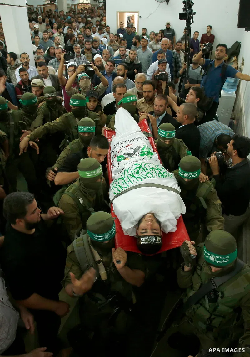 Palestinian mourners and fighters from the Ezzedine al-Qassam Brigades, the armed wing of the Palestinian Hamas movement, carry the body of 22-year-old Mohammed Alagha in Khan Yunis, in the southern Gaza Strip, on Octobe...