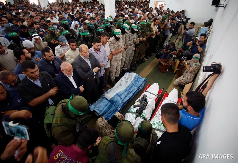 Palestinian mourners and fighters from the Ezzedine al-Qassam Brigades, the armed wing of the Palestinian Hamas movement pray around the bodies of 30-year-old Mosbah Shabir and Mohammed Alagha,22, in Khan Yunis, in the s...