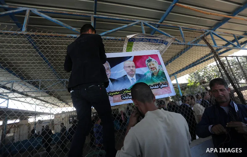 Palestinian men put up a poster displaying Palestinian leader Mahmud Abbas (L), prime minister Rami Hamdallah and late leader Yasser Arafat, at Erez crossing, in the northern Gaza Strip November 1, 2017. Hamas handed ove...