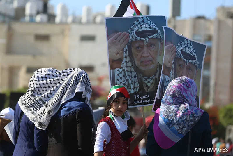Palestinians hold national flags and posters of the late Palestinian leader Yasser Arafat during a festival to commemorate the 13th anniversary of his death, in Gaza City on November 9, 2017. Photo by Mohammed Dahman