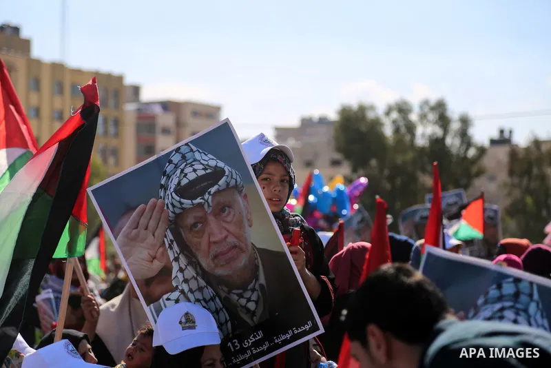 Palestinians hold national flags and posters of the late Palestinian leader Yasser Arafat during a festival to commemorate the 13th anniversary of his death, in Gaza City on November 9, 2017. Photo by Mohammed Dahman