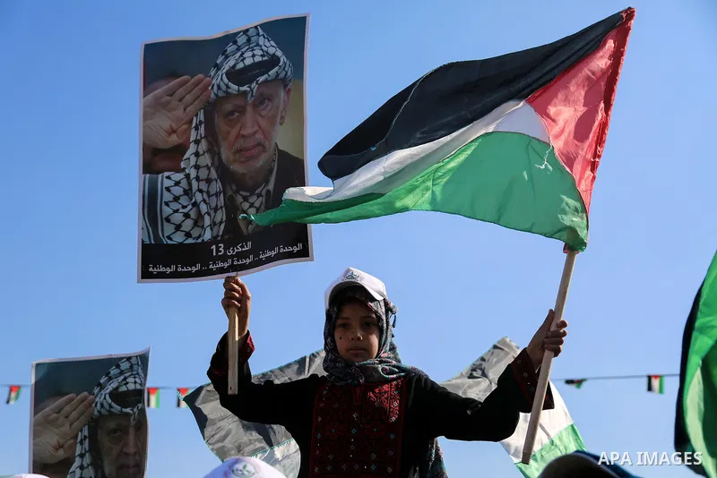 Palestinians hold national flags and posters of the late Palestinian leader Yasser Arafat during a festival to commemorate the 13th anniversary of his death, in Gaza City on November 9, 2017. Photo by Mohammed Dahman