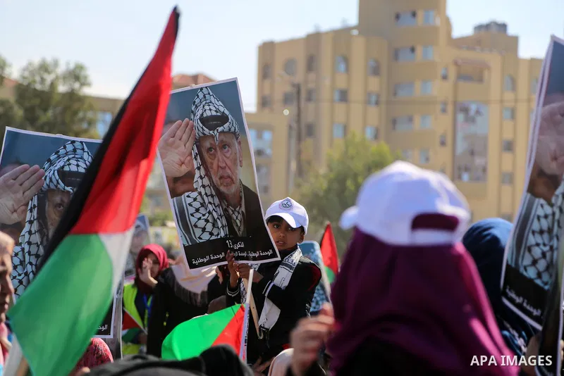 Palestinians hold national flags and posters of the late Palestinian leader Yasser Arafat during a festival to commemorate the 13th anniversary of his death, in Gaza City on November 9, 2017. Photo by Mohammed Dahman
