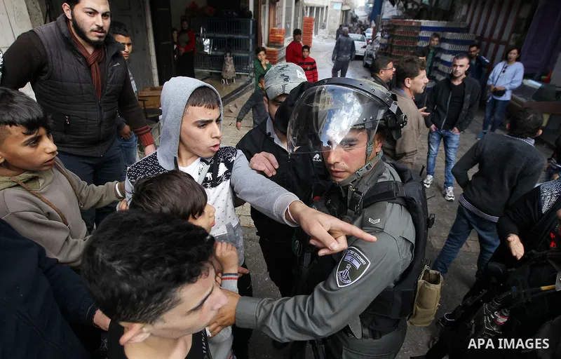 A Palestinian boy argues with an Israeli soldier as Israeli settlers walk towards the tomb of Atnaeil Ben Kinaz, a Jewish religious site during an annual pilgrimage organised by Israel's settler movement on the occasion...
