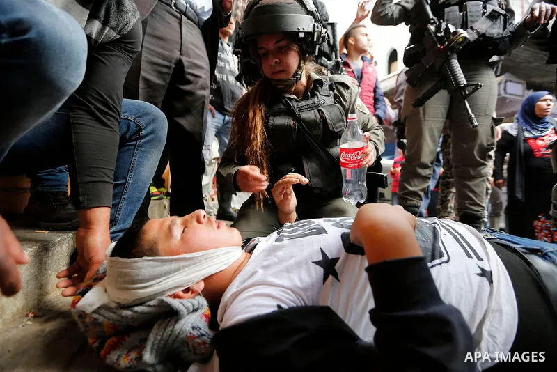 An injured Palestinian boy lies after an Israeli soldier hits him as Israeli settlers walk towards the tomb of Atnaeil Ben Kinaz, a Jewish religious site during an annual pilgrimage organised by Israel's settler movement...