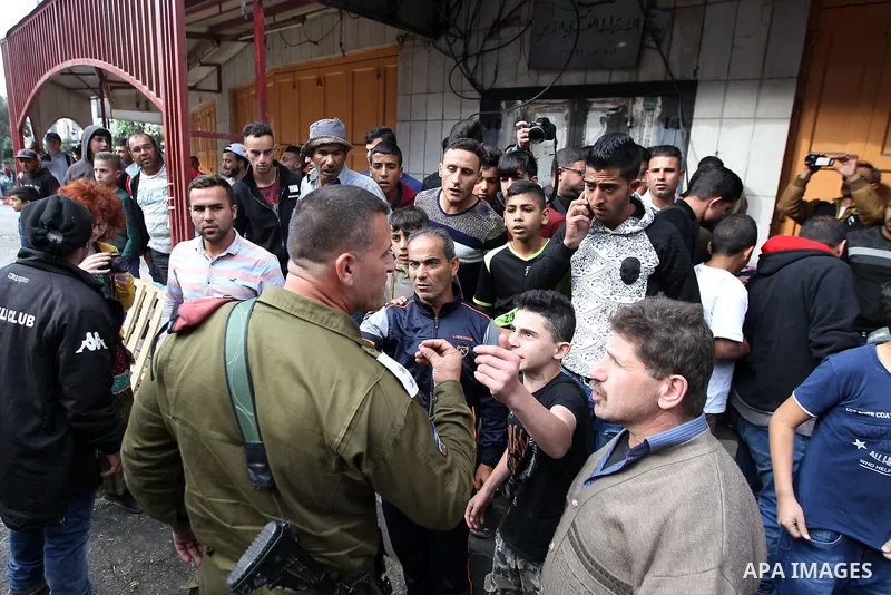 A Palestinian boy argues with an Israeli soldier as Israeli settlers walk towards the tomb of Atnaeil Ben Kinaz, a Jewish religious site during an annual pilgrimage organised by Israel's settler movement on the occasion...