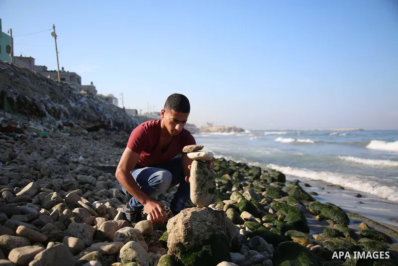 A Palestinian youth Ahmed Al Awadi performs rock balancing at the beach of Gaza city on November 16, 2017. Rock balancing is a performance art which involves arranging natural stones usually found on location, in gravity...