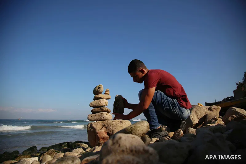 A Palestinian youth Ahmed Al Awadi performs rock balancing at the beach of Gaza city on November 16, 2017. Rock balancing is a performance art which involves arranging natural stones usually found on location, in gravity...