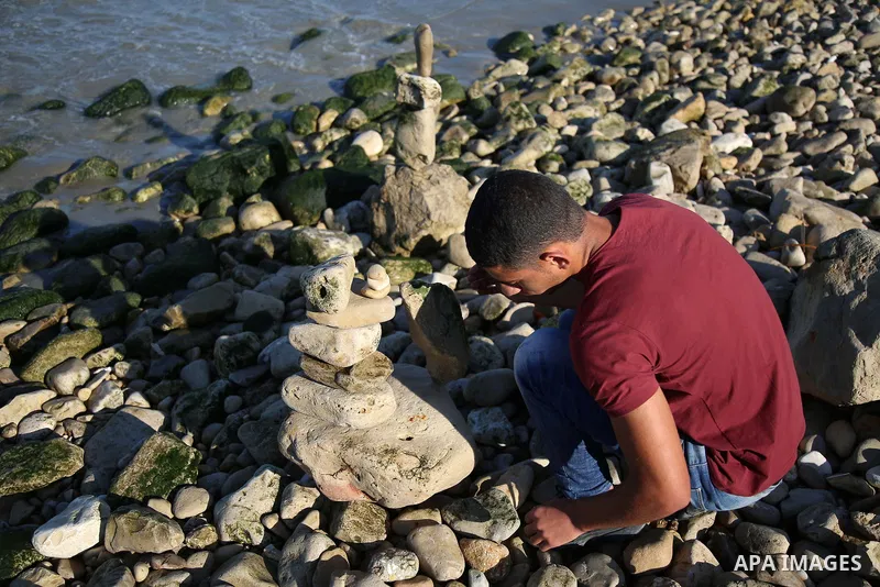 A Palestinian youth Ahmed Al Awadi performs rock balancing at the beach of Gaza city on November 16, 2017. Rock balancing is a performance art which involves arranging natural stones usually found on location, in gravity...