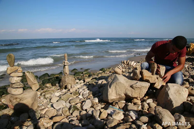 A Palestinian youth Ahmed Al Awadi performs rock balancing at the beach of Gaza city on November 16, 2017. Rock balancing is a performance art which involves arranging natural stones usually found on location, in gravity...