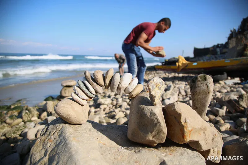 A Palestinian youth Ahmed Al Awadi performs rock balancing at the beach of Gaza city on November 16, 2017. Rock balancing is a performance art which involves arranging natural stones usually found on location, in gravity...
