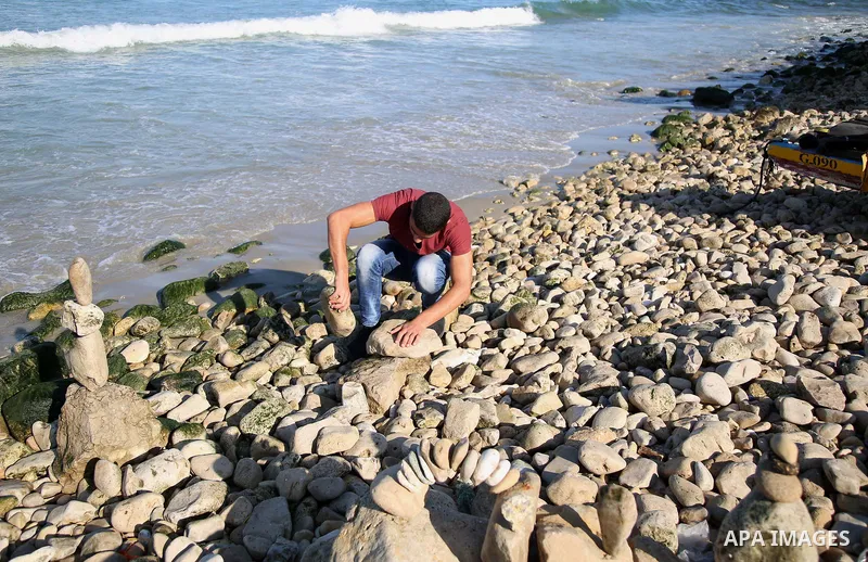 A Palestinian youth Ahmed Al Awadi performs rock balancing at the beach of Gaza city on November 16, 2017. Rock balancing is a performance art which involves arranging natural stones usually found on location, in gravity...