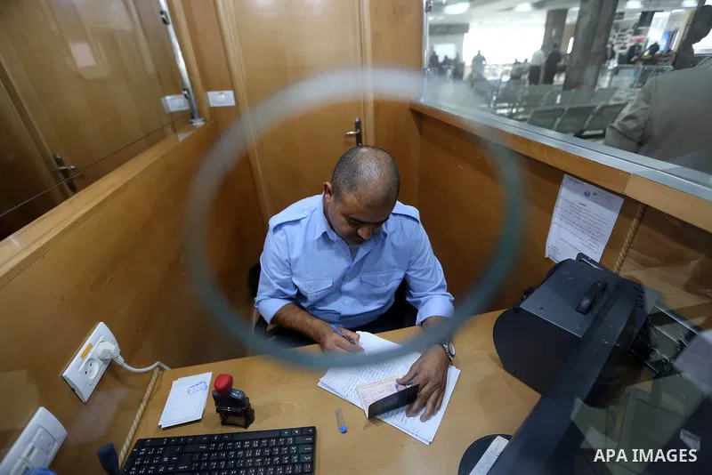 A Palestinian passport control officer latter checks travel passengers documents before allowing them through the Rafah border crossing with Egypt, under the control of the Palestinian Authority, in the southern Gaza Str...