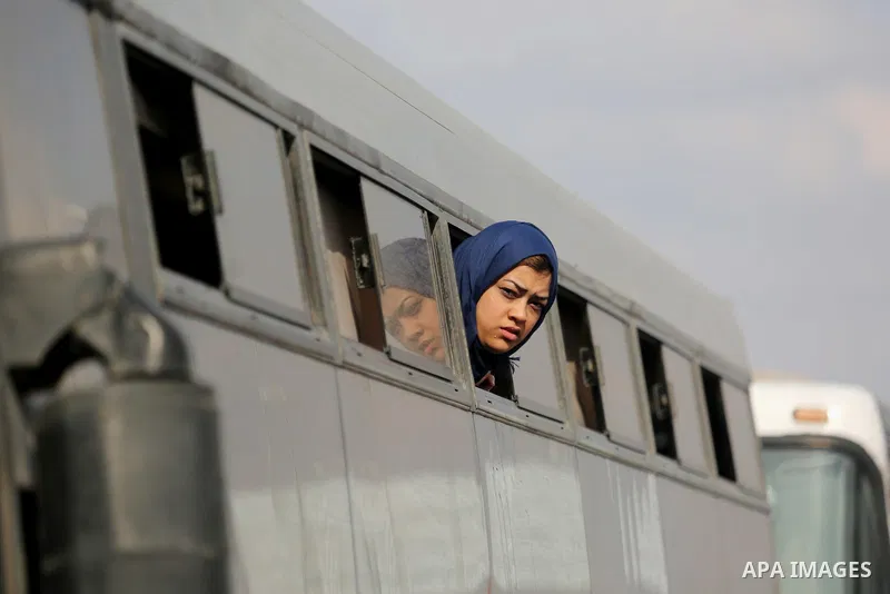 A Palestinian woman looks through a bus window waiting at the Rafah border crossing with Egypt before being allowed to pass out of the southern Gaza Strip on November 20, 2017, following its opening for three days for th...