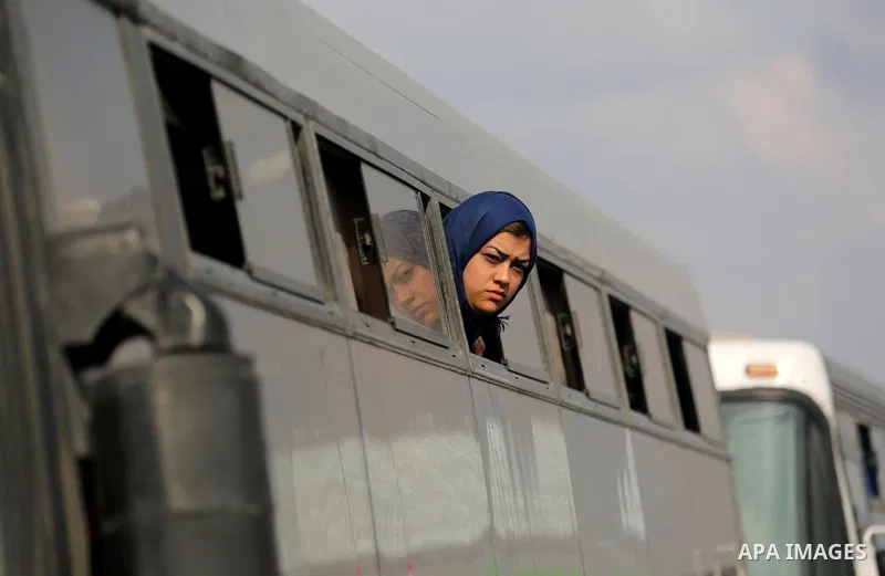 A Palestinian woman looks through a bus window waiting at the Rafah border crossing with Egypt before being allowed to pass out of the southern Gaza Strip on November 20, 2017, following its opening for three days for th...
