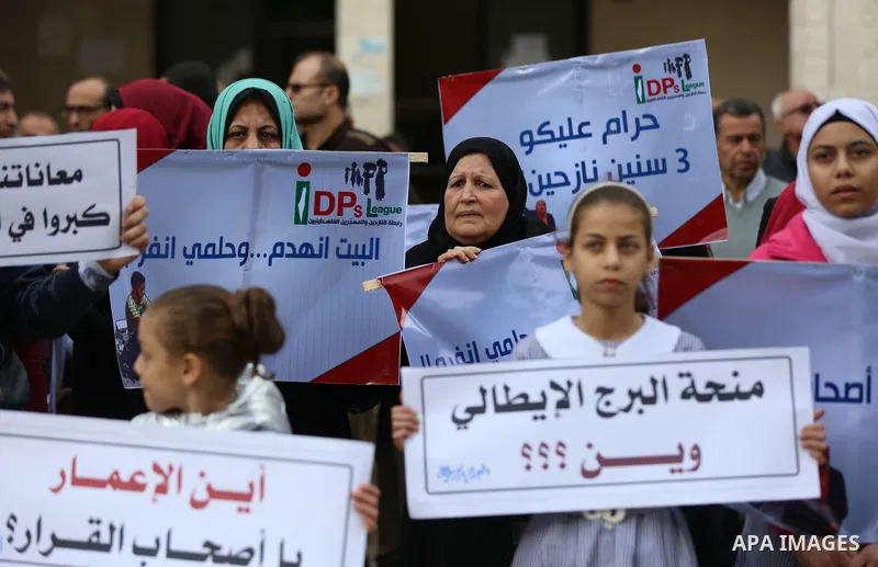 Palestinian residents of the Italian tower hold banners during a protest demanding to reconstruction their houses which was destroyed during the 50-day war between Israel and Hamas militants in the summer of 2014, in Gaz...