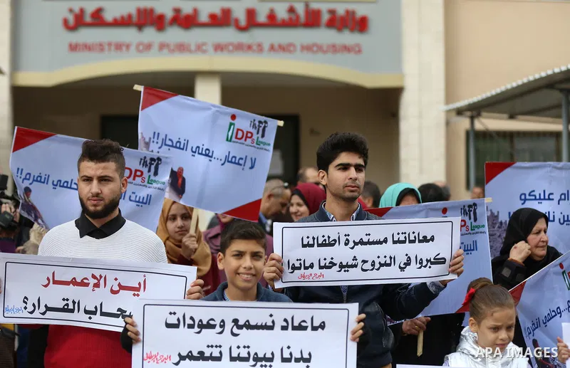 Palestinian residents of the Italian tower hold banners during a protest demanding to reconstruction their houses which was destroyed during the 50-day war between Israel and Hamas militants in the summer of 2014, in Gaz...