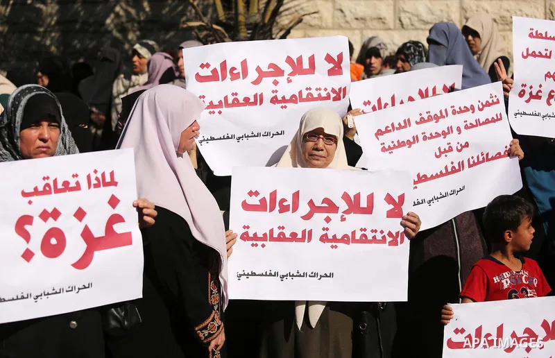 Palestinians hold placards during a demonstration against the siege, in front of Palestinian government headquarters in Gaza City on December 4, 2017. Photo by Ashraf Amra