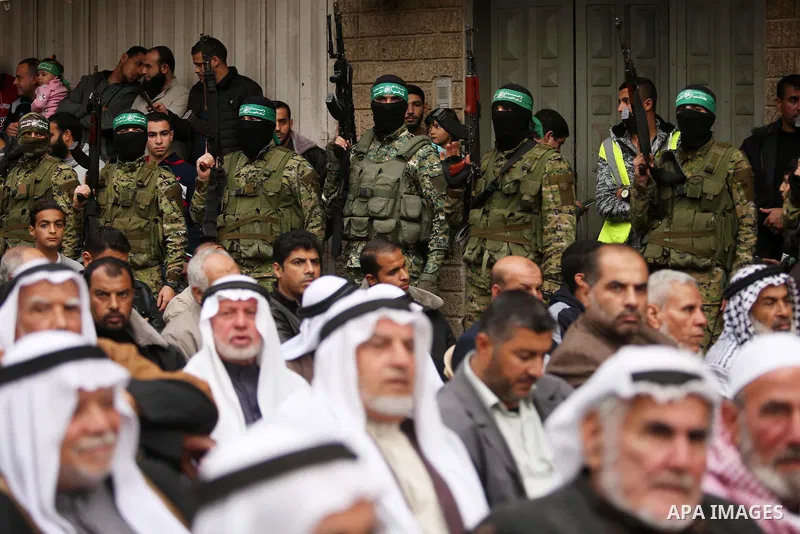 Palestinians watch as members of the Ezzedine al-Qassam Brigades, the military wing of the Palestinian Islamist movement Hamas take part during a military parade ahead of the 30th anniversary of Hamas' founding, in Khan...