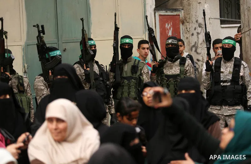Palestinians watch as members of the Ezzedine al-Qassam Brigades, the military wing of the Palestinian Islamist movement Hamas take part during a military parade ahead of the 30th anniversary of Hamas' founding, in Khan...