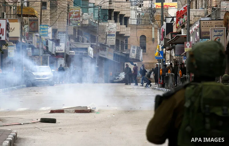 Palestinians clash with Israeli troops during a protest against U.S. President Donald Trump's decision to recognize Jerusalem as the capital of Israel in the West Bank City of Hebron, Thursday, Dec. 7, 2017. Photo by Wis...