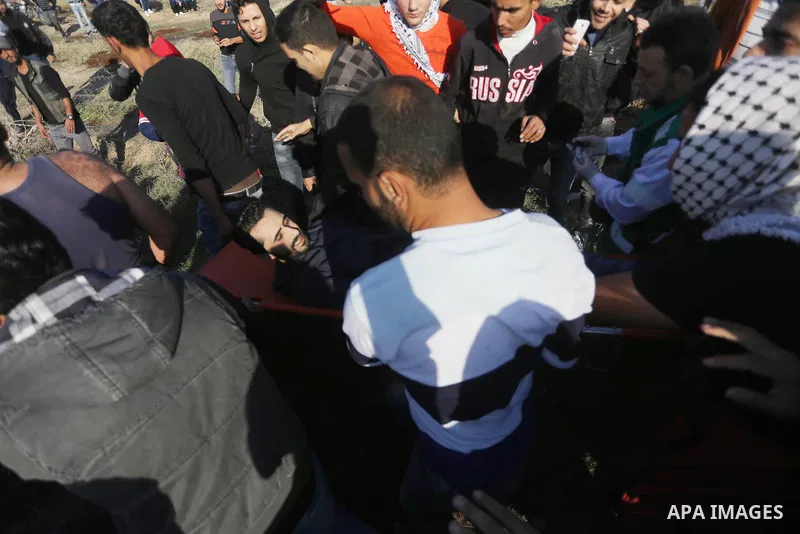 Palestinian protesters carry a wounded comrade during clashes with Israeli forces on December 8, 2017 near the border fence with Israel, east of Gaza City. Palestinians clashed with Israeli security forces after calls fo...