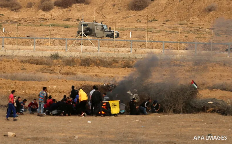 Palestinian protesters gather behind a heap of barbed wire and smoke from burning tires, during clashes with Israeli forces near the Israel-Gaza border east of the southern Gaza strip city of Khan Yunis on December 10, 2...