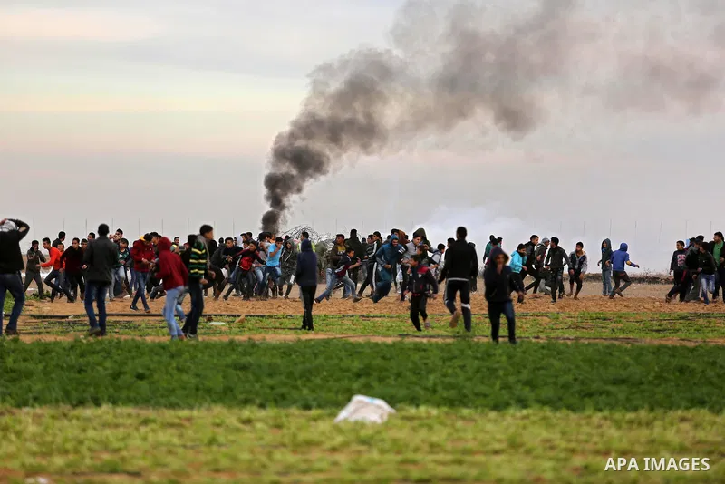 Palestinian protesters run through tear gas fumes during clashes with Israeli forces near the Israel-Gaza border east of the southern Gaza strip city of Khan Yunis on December 10, 2017, with Israeli heavy machinery seen...
