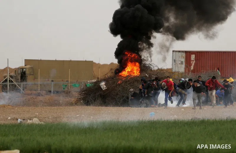 Palestinian protesters gather behind a heap of barbed wire and smoke from burning tires, during clashes with Israeli forces near the Israel-Gaza border east of the southern Gaza strip city of Khan Yunis on December 10, 2...
