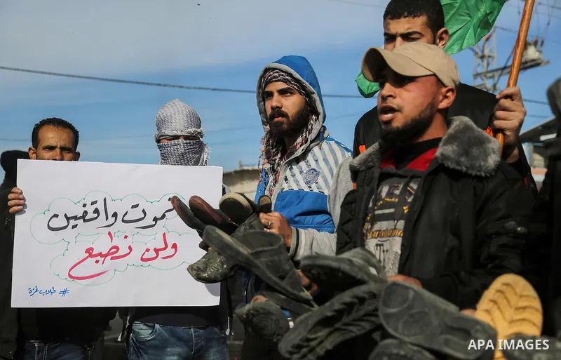 Palestinian demonstrators hold banners during a protest against what organizers said was a visit by a group of Bahraini people to Israel, in the northern Gaza Strip December 11, 2017. Photo by Mohammed Dahman