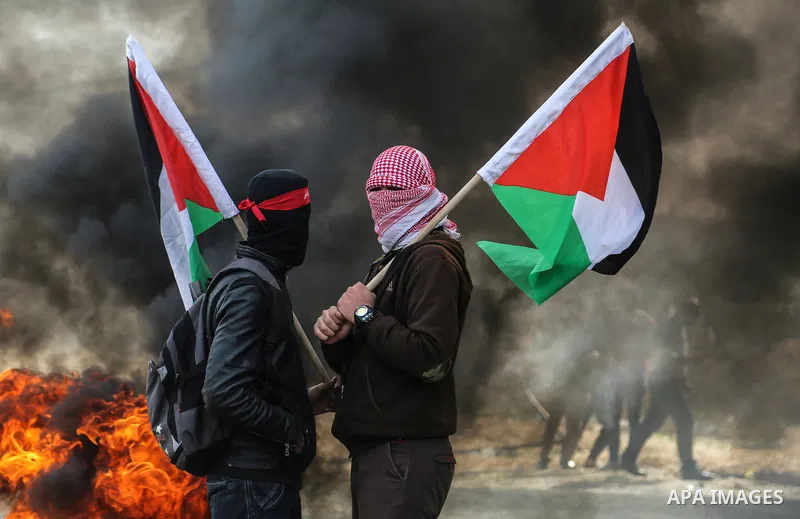 Palestinian demonstrators hold Palestine flags during a protest against what organizers said was a visit by a group of Bahraini people to Israel, in the northern Gaza Strip December 11, 2017. Photo by Mohammed Dahman