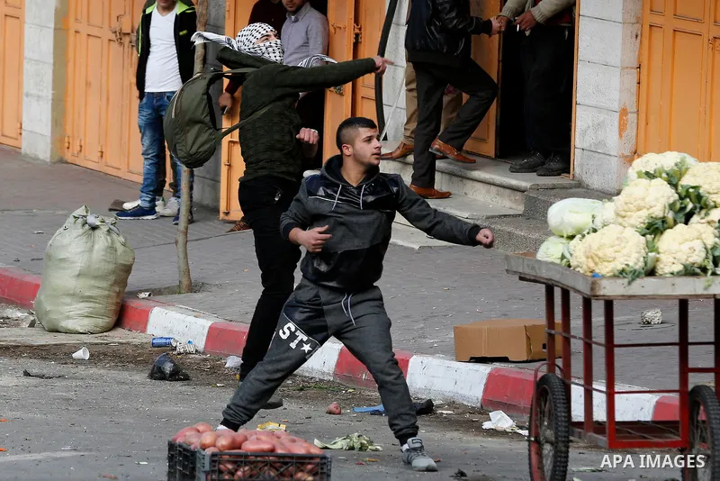 Palestinian protesters hurl stones towards Israeli secrity forces during clashes behind a checkpoint in the city centre of the West Bank town of Hebron on December 11, 2017 as demonstrations continue to flare in the Midd...