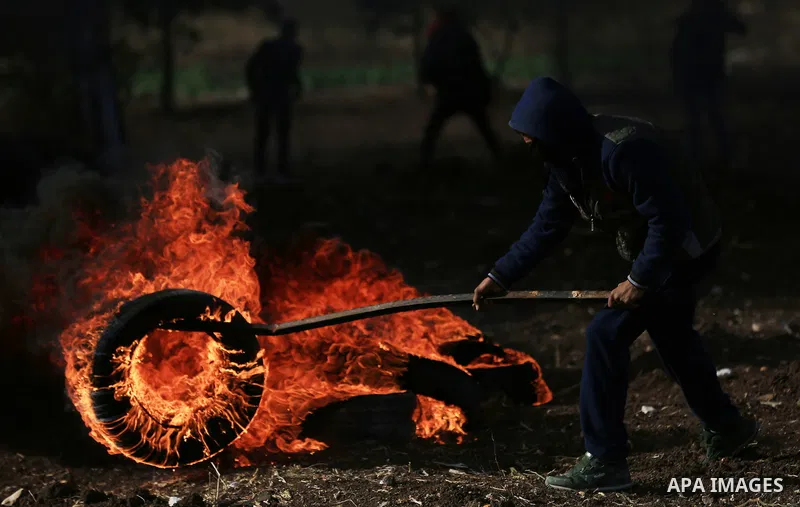 A Palestinian protester burns tires during clashes with Israeli security forces in the West Bank town of Tulkarem, following a demonstration against US President Donald Trump's decision to recognise Jerusalem as the capi...