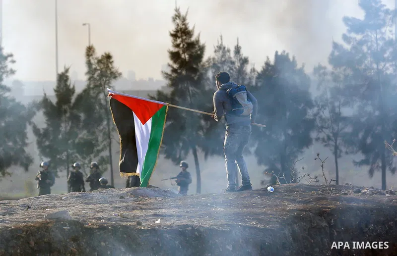 A Palestinian protester holds the national flag during clashes with Israeli security forces in the West Bank town of Tulkarem, following a demonstration against US President Donald Trump's decision to recognise Jerusalem...