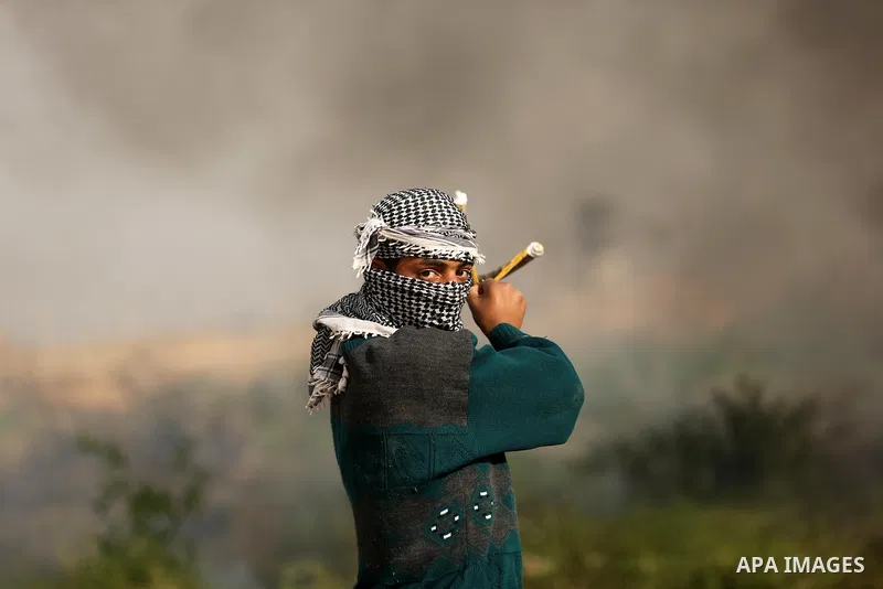A Palestinian protester uses a slingshot to hurl stones towards Israeli security forces during clashes near the Israel-Gaza border east of the southern Gaza strip city of Khan Yunis on December 12, 2017 with Israeli heav...