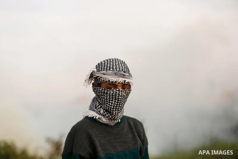 A Palestinian protester gestures to the camera during clashes with Israeli security forces near the Israel-Gaza border east of the southern Gaza strip city of Khan Yunis on December 12, 2017 with Israeli heavy machinery...