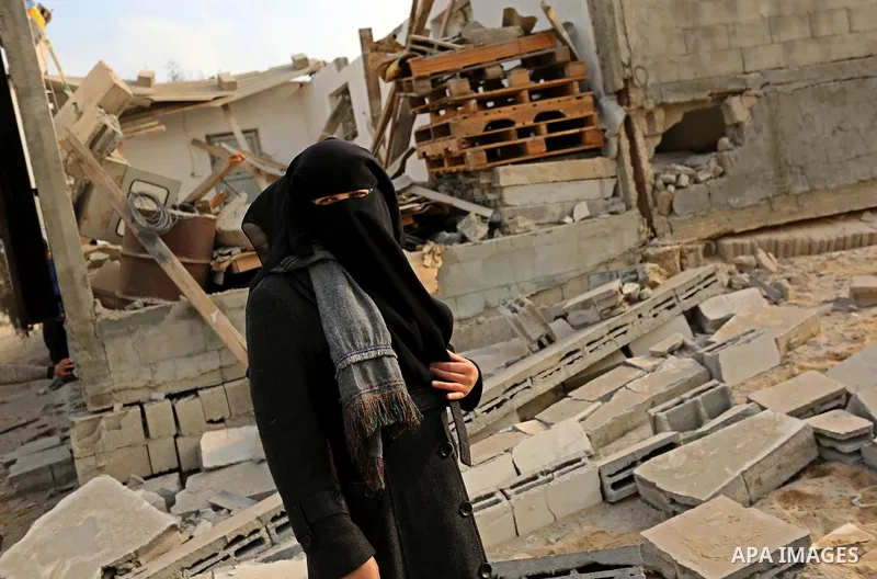 A Palestinian woman inspects her house that was damaged in an Israeli airstrike on a nearby Hamas base, in Khan Yunis town in the southern Gaza Strip in December 13, 2017. Photo by Ashraf Amra