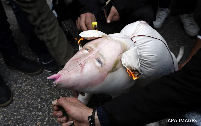 Palestinian protestors burn stuffed pillows in the shape of a pig and bearing an image of Israeli President Benjamin Netanyahu during a demonstration in the West Bank town of Hebron on December 13, 2017. Photo by Wisam H...