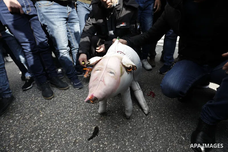 Palestinian protestors burn stuffed pillows in the shape of a pig and bearing an image of Israeli President Benjamin Netanyahu during a demonstration in the West Bank town of Hebron on December 13, 2017. Photo by Wisam H...