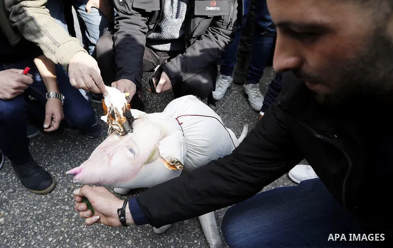 Palestinian protestors burn stuffed pillows in the shape of a pig and bearing an image of Israeli President Benjamin Netanyahu during a demonstration in the West Bank town of Hebron on December 13, 2017. Photo by Wisam H...