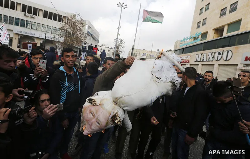 Palestinian protestors burn stuffed pillows in the shape of a pig and bearing an image of Israeli President Benjamin Netanyahu during a demonstration in the West Bank town of Hebron on December 13, 2017. Photo by Wisam H...