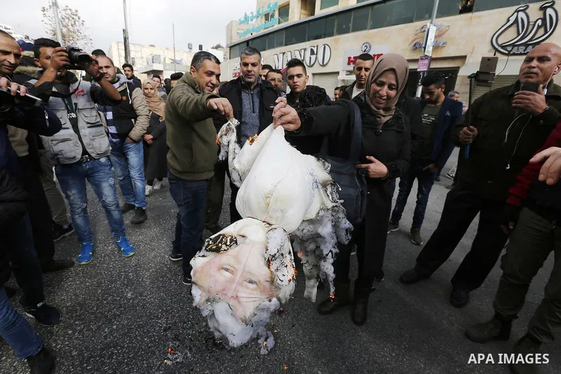 Palestinian protestors burn stuffed pillows in the shape of a pig and bearing an image of Israeli President Benjamin Netanyahu during a demonstration in the West Bank town of Hebron on December 13, 2017. Photo by Wisam H...