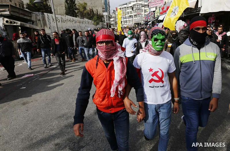 Palestinian protestors wave their national flag and shout slogans during a demonstration in the West Bank town of Hebron on December 13, 2017. Photo by Wisam Hashlamoun