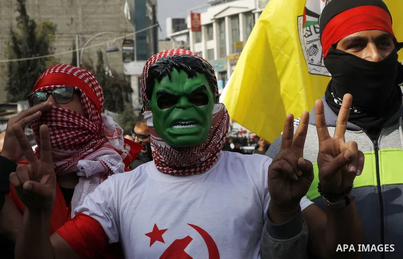 Palestinian protestors wave their national flag and shout slogans during a demonstration in the West Bank town of Hebron on December 13, 2017. Photo by Wisam Hashlamoun