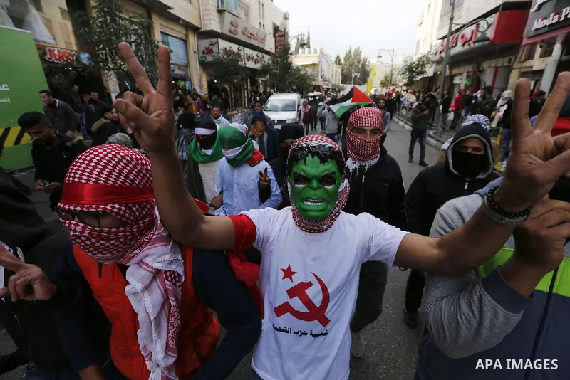 Palestinian protestors wave their national flag and shout slogans during a demonstration in the West Bank town of Hebron on December 13, 2017. Photo by Wisam Hashlamoun