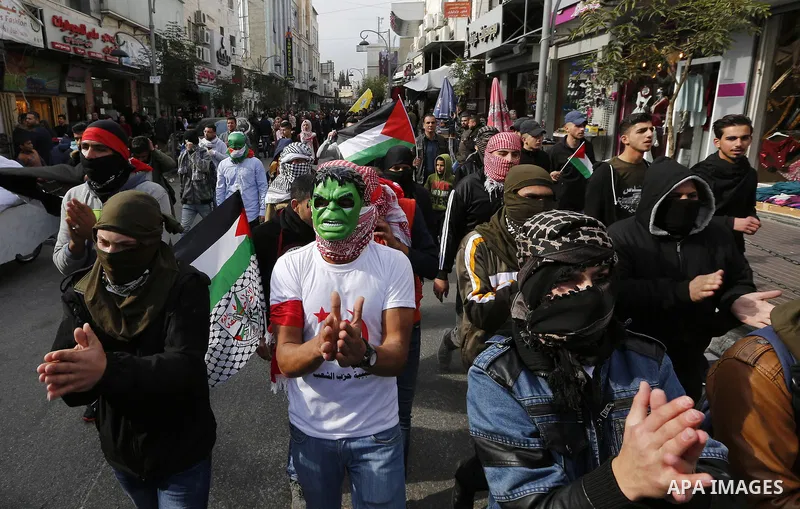 Palestinian protestors wave their national flag and shout slogans during a demonstration in the West Bank town of Hebron on December 13, 2017. Photo by Wisam Hashlamoun